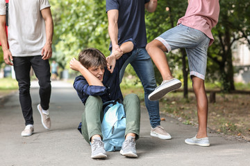 Aggressive teenagers bullying boy outdoors