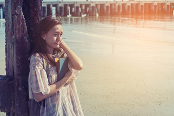 loneliness concept; woman sitting on the beach and missing about love story