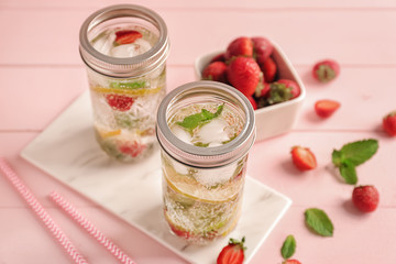 Jars of fresh strawberry lemonade on color wooden table