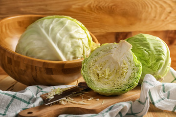 Whole and cut fresh cabbage on wooden table