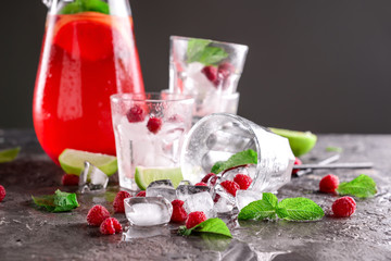 Fresh summer cocktail in jug and glasses with ice cubes on grey table