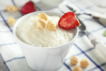 Delicious rice pudding with strawberry and hazelnuts in bowl on table