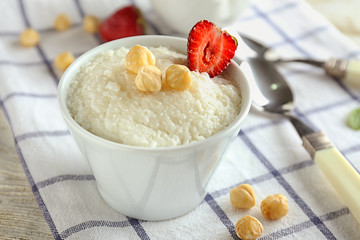 Delicious rice pudding with strawberry and hazelnuts in bowl on table