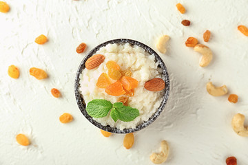 Delicious rice pudding with dried fruits and almonds in bowl on light table