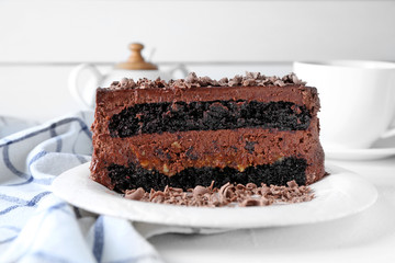 Plate with piece of delicious chocolate cake on light table