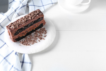 Plate with piece of delicious chocolate cake on light table
