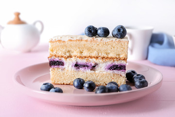 Plate with piece of delicious blueberry cake on color wooden table