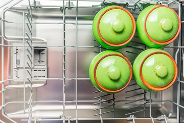 Four green ceramic pots lie in the lower compartment of the dishwasher