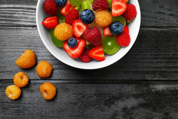 Delicious fruit salad in bowl on dark wooden table