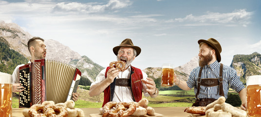 Germany, Bavaria. The happy smiling singing men with beer dressed in traditional Austrian or...