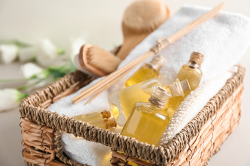 Bottles with essential oil and towel in wicker basket