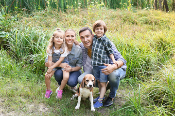 Obraz premium Happy family with cute dog resting in park
