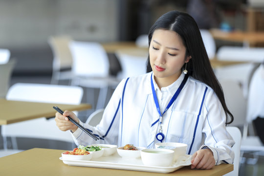 Asian Female White-collar Worker Eating In The Cafeteria