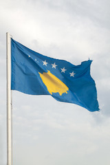 Flag of Kosovo on a blue sky with clouds background