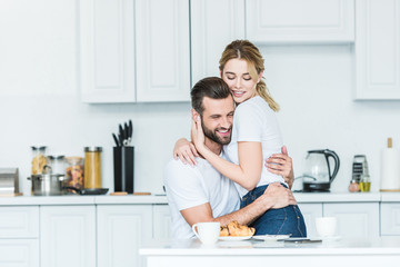 beautiful happy young couple in love hugging during breakfast in kitchen