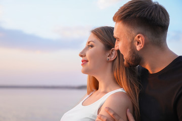 Happy loving couple near river at sunset