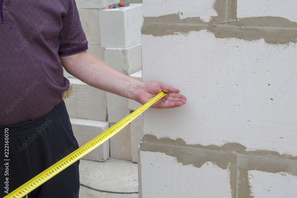 Poster close up view of the hand holding the measuring tape next to the foam block. the customer measures t