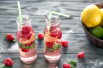 Fototapeta na wymiar Bottles of fresh raspberry lemonade on wooden table