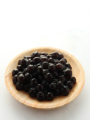 High angle view of tapioca ball (also known as boba in bubble tea) on wooden plate isolated on white background. Ingredients for making pearl milk tea and shaved ice at dessert shop. Food concept.