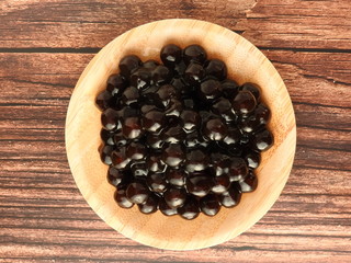 Top view of tapioca ball (also known as boba in bubble tea) on wooden plate isolated on wooden...