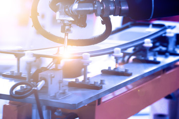 On the assembly line of the automobile manufacturing plant, the robot arm is being glued to the car window glass.