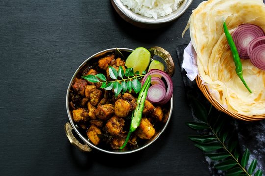 Kerala Pork Fry or Roast served with Parotta and rice on black background
