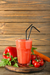 Glass of tasty red smoothie and vegetables on wooden board