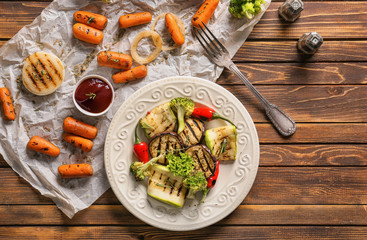 Plate with tasty grilled vegetables and tomato sauce on wooden table