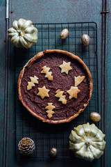 Christmas pie make with quince and cinnamon jam with biscuits decoration above over a concrete kind background with decoration and kitchen tools around