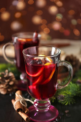 Glass cup of delicious mulled wine on wooden table against blurred lights