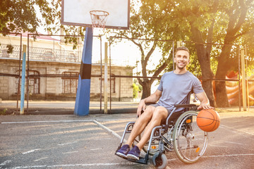 Young man in wheelchair playing basketball outdoors