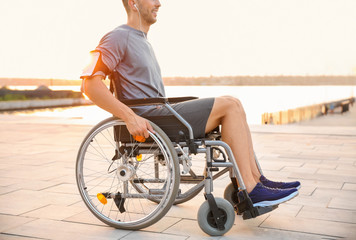 Young man in wheelchair listening to music outdoors