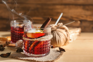 Glass of delicious hot mulled wine on wooden table