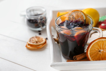 Glass cup of delicious hot mulled wine on tray