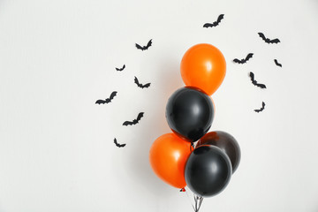 Color balloons with paper bats for Halloween party on light background