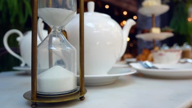Sand clock (hourglasses) on the tea table while waiting for the tea to be ready (crystal sand clock) with tea pot in the background