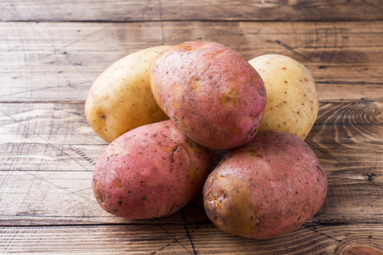 Raw potato red and yellow food. Fresh potatoes on wooden background.