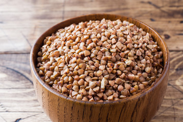 Buckwheat raw in a wooden bowl on a rustic wooden background.