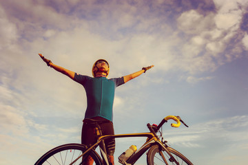 Biking cyclist male standing open arms with bicycle morning sky