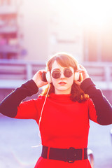 young woman outdoor in the city listening music headphones looking camera - music, relaxing,...