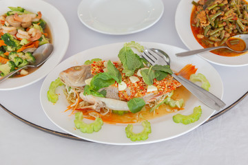 Fried fish topped with fresh herbs and sweet spicy sauce on plate.Thai Food