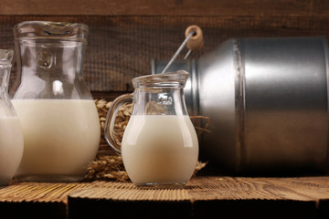 A jug of milk and glass of milk on a wooden table