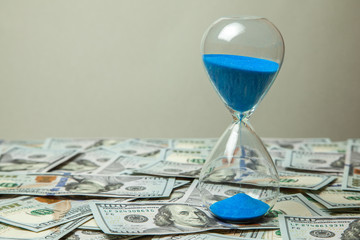 Hourglass and money dollars banknotes. Time is money