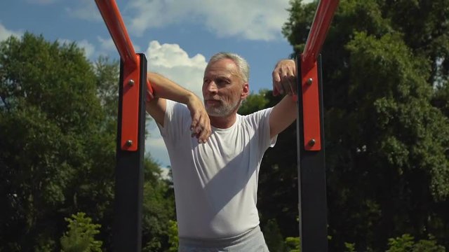 Attractive handsome strong men standing near bars rest after training, slow-mo
