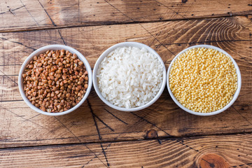 Dry groats grocery. Rice, buckwheat and millet on the wooden background.