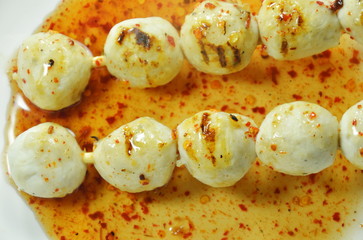 grilled pork ball stabbing in wooden stick dressing spicy and sweet sauce on plate