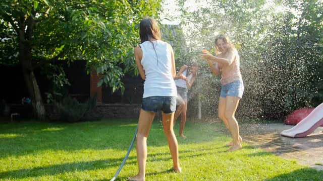 Slow Motion Video Of Cheerful Family Splashing Water Over Each Other From Garden Hose And Toy Guns