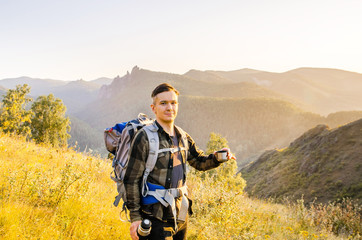 Fototapeta na wymiar Young traveler with a thermos of tea on a mountain background.