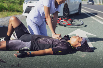 Female nurse helping emergency CPR to asia cyclist injured on the street bike after collision...