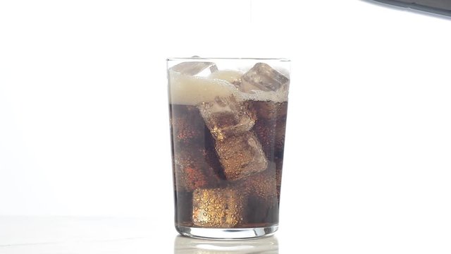Vertiendo refresco de cola en un vaso con hielos